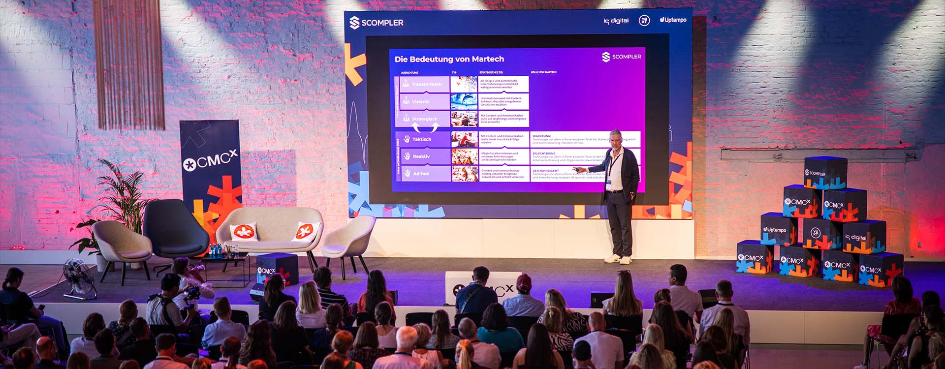 Mann hält einen Vortrag auf einer Bühne vor Publikum