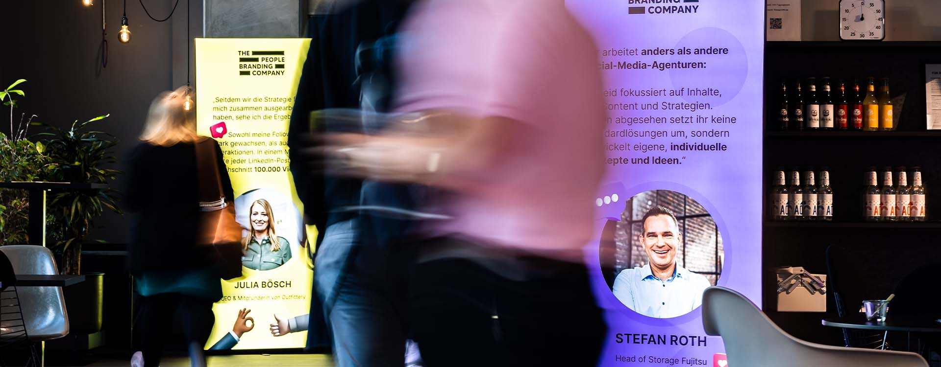 Messebesucher gehen an leuchtender Messewand vorbei