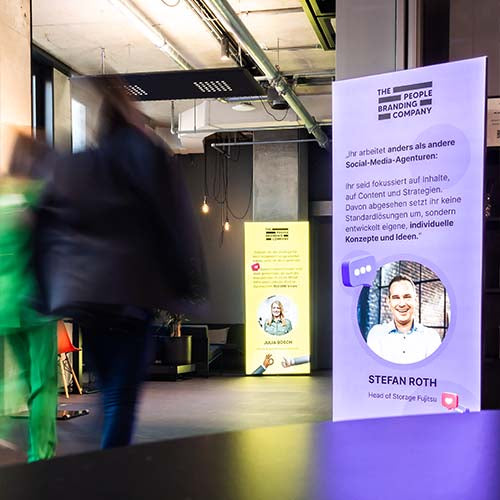 Menschen gehen an leuchtenden STAGEMee Rollups vorbei